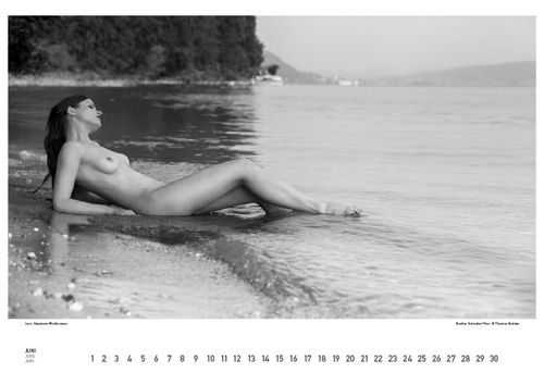 Zwart-wit foto van een naakte vrouw op het strand bij een meer