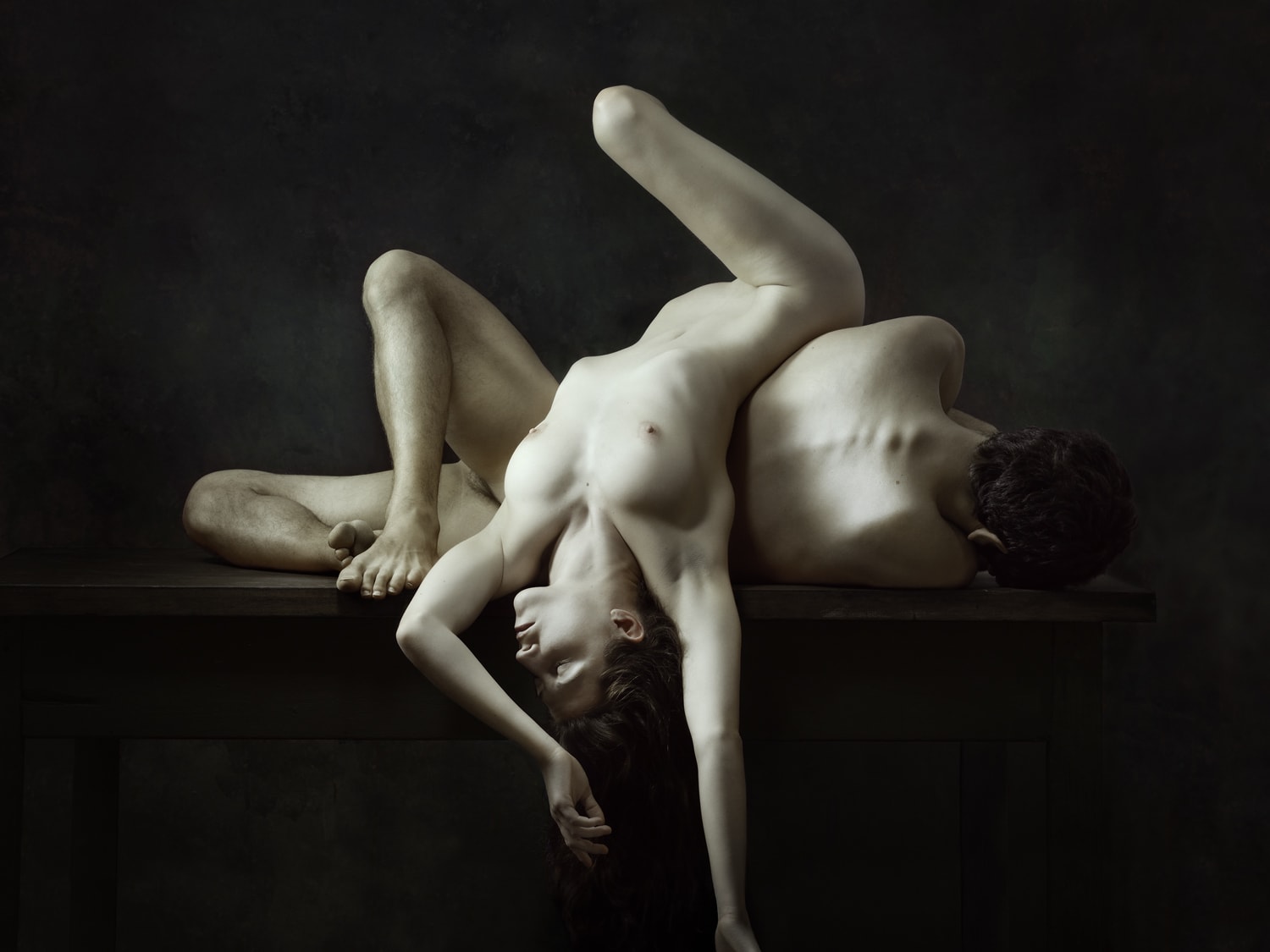 Naakte man en vrouw in een abstracte pose op een tafel in sepia