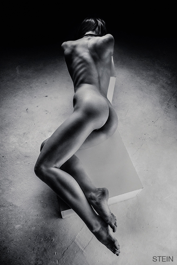 Prachtig abstracte naaktfoto van een model op een blok in de studio, in zwart-wit
